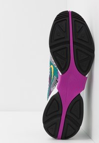 Nike-sneaker med en flerfärgad mesh-ovandel, vita accenter och en svart gummisula med en lila mellansula och texturerade detaljer.