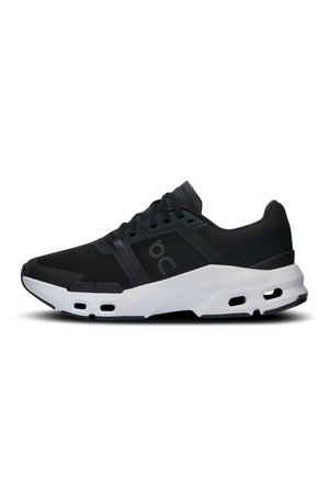 Baskets de sport noires avec une tige en maille respirante, semelle en caoutchouc et accents blancs. Présentent un design rembourré et de soutien avec des trous de ventilation visibles.