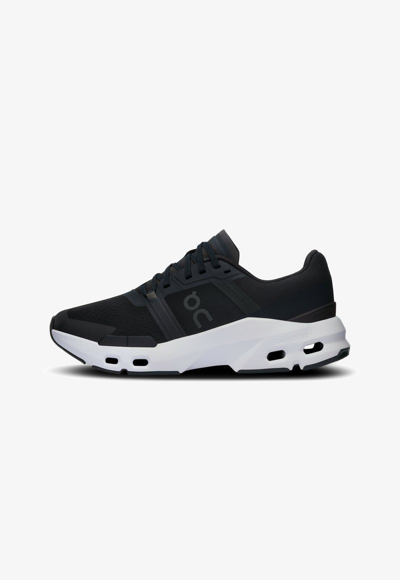 Scarpe da ginnastica nere con tomaia in rete traspirante, suola in gomma e dettagli bianchi. Presentano un design imbottito e di supporto con fori di ventilazione visibili.