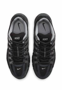 Μαύρα αθλητικά παπούτσια από δίχτυ με γκρι λεπτομέρειες, που διαθέτουν στρογγυλεμένη μύτη, σχεδιασμό με κορδόνια και έντονη σήμανση Nike στη γλώσσα και στις πλευρές.
