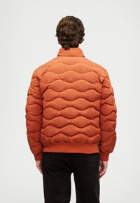 Gumena narančasta jakna s punjenjem, s rebrastim ovratnikom i manžetama, s teksturiranom završnom obradom i horizontalnim uzorkom.