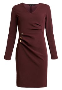 Burgundy långärmad klänning med v-ringning, med en rynkad sidodesign och tre accentknappar i guldton vid midjan. Mjuk tygtextur.