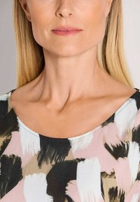 Blouse met patroon met abstracte penseelstreek in roze, zwart en crème. Ronde halslijn en gladde stoftextuur.