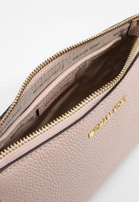 Borsa a tracolla in pelle rosa con superficie testurizzata, minuteria dorata e fodera interna con un motivo a logo ripetuto.