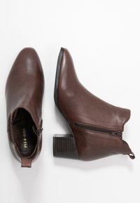 Bottes de cheville en cuir marron avec un bout pointu, une fermeture éclair sur le côté et un talon bloc. Le talon texturé ajoute une touche de détail à ce design élégant.