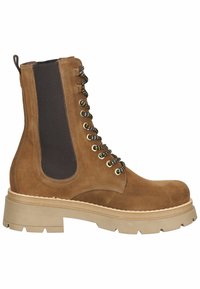 Botte lacée en daim marron avec panneau latéral élastique noir et semelle beige épaisse, conçue pour un usage décontracté ou robuste.