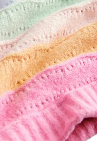 Wielokolorowe warstwy filcowego materiału w pastelowych odcieniach: zielonym, lawendowym, różowym, brzoskwiniowym i intensywnie różowym. Posiada teksturowane wzory i wytłaczane krawędzie.