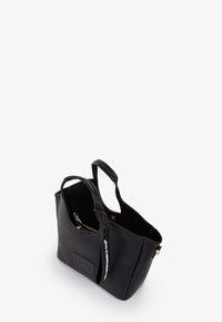 Sort tekstureret læder totebag med to håndtag, lynlåsåbning og et logo præget på forsiden. Indersiden ser rummelig ud med en lynlåslomme.