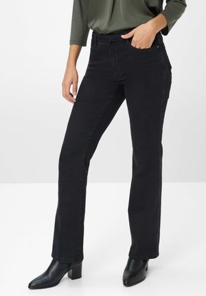Schwarze Jeans aus Denim mit geradem Schnitt, fünf Taschen und mittlerer Taillenhöhe, kombiniert mit schwarzen, hochhackigen Stiefeletten. Glatte Textur und minimale Details.