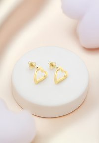 Orecchini a forma di cuore in oro con finitura liscia, montati su una base rotonda bianca. Presentano una chiusura a farfalla per un'indossabilità sicura.