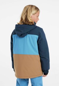 Färgsprakande jacka med mörk marinblå, ljusblå och bruna sektioner, med huva och elastiska ärmslut, tillverkad av ett smidigt, hållbart material.