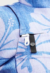 Μπλε ύφασμα με λουλουδάτο σχέδιο, λευκό τράβηγμα φερμουάρ και μαύρο κουμπί snap σε μαύρο λουράκι.