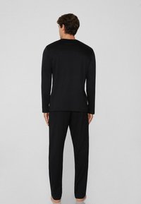 Schwarzes Langarmshirt und passende Hose, gefertigt aus weichem Stoff mit lockerer Passform, ausgestattet mit einem runden Halsausschnitt und ohne sichtbare Muster.