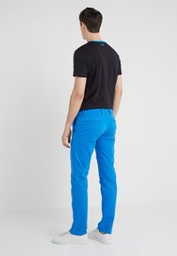 Czarny t-shirt z niebieskimi akcentami, w połączeniu z jasnoniebieskimi spodniami. Strój ma casualowy krój, widoczne kieszenie i białe trampki.