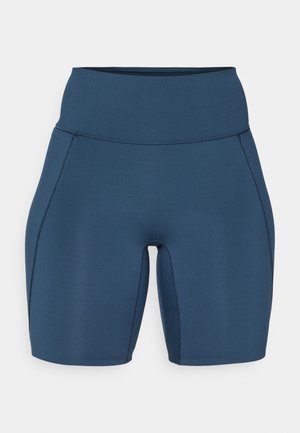 Tmavo modré športové šortky s vysokým pásom, hladkým povrchom a plochými švami. Majú priliehavý strih, ktorý siaha do polovice stehien.