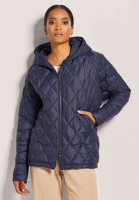 Marineblau gesteppte Puffjacke mit Kapuze, vorderem Reißverschluss und seitlichen Taschen. Es verfügt über eine glatte, glänzende Textur und ein durchgehendes Rautenmuster.