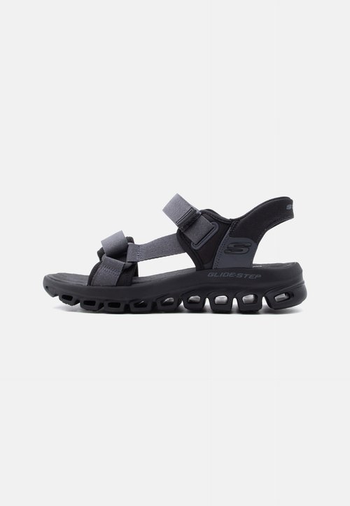 Sandale noire et grise à bout ouvert avec des sangles réglables et une semelle rembourrée dotée d'une unité d'air visible, étiquetée "Glide-Step."