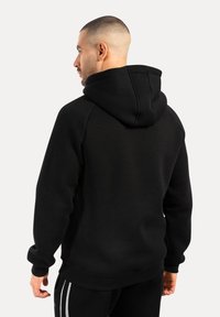 Sort hætte sweatshirt med ribbede manchetter og kant. Blød tekstur, afslappet pasform, med en stor hætte og minimalistiske designelementer.