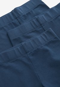 Marineblaue Leggings gestapelt, mit elastischem Bund, glatter Textur und Logodetail. Konsistente Farbe und Material überall.