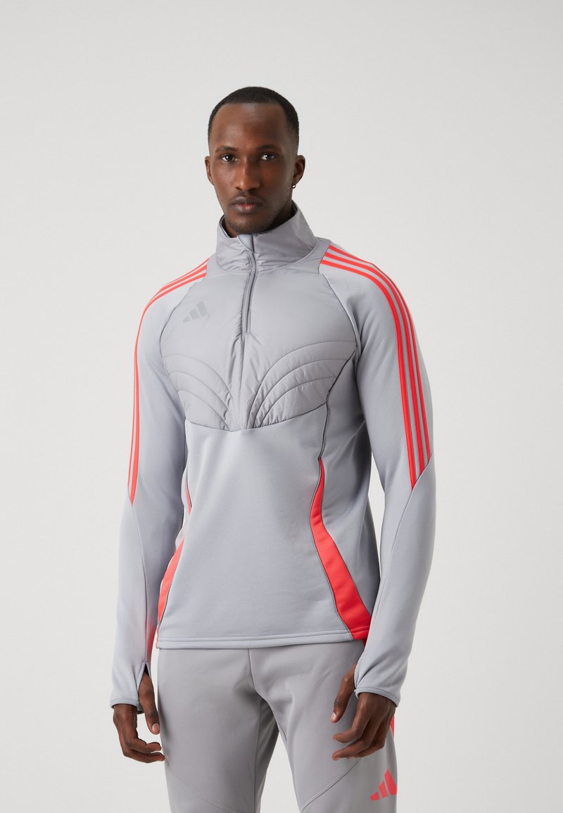 Grijze sportjacket met roze accenten, halve ritssluiting aan de voorkant, hoge kraag, gestructureerde panelen op de borst en drievoudige streep design op de mouwen.