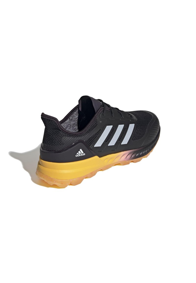 Baskets noires de sport avec une tige en mesh texturé, trois rayures blanches et une semelle intermédiaire jaune. Équipées d'une semelle extérieure en caoutchouc avec un relief visible.