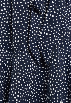 Navy dress with white polka dots, featuring a smooth fabric texture, a bow detail at the neck, and a flared skirt design.