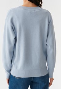 Jasnoniebieski sweter dziany z okrągłym dekoltem, ściągaczami na mankietach i u dołu. Miękka tekstura i luźny krój, pokazany od tyłu.