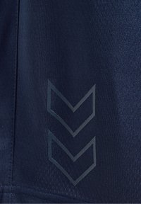 Gros plan sur un tissu bleu foncé avec deux formes de flèches chevrons bleu clair pointant vers le bas.