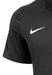Zwart poloshirt van gladde stof, met een wit Nike-logo op de linkerkant van de borst en een klassieke kraag met korte mouwen.