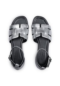 Sandales plates métalliques argentées avec design de bride tissée, semelle en cuir noir et bride de cheville. Présentent une finition texturée et une boucle réglable.