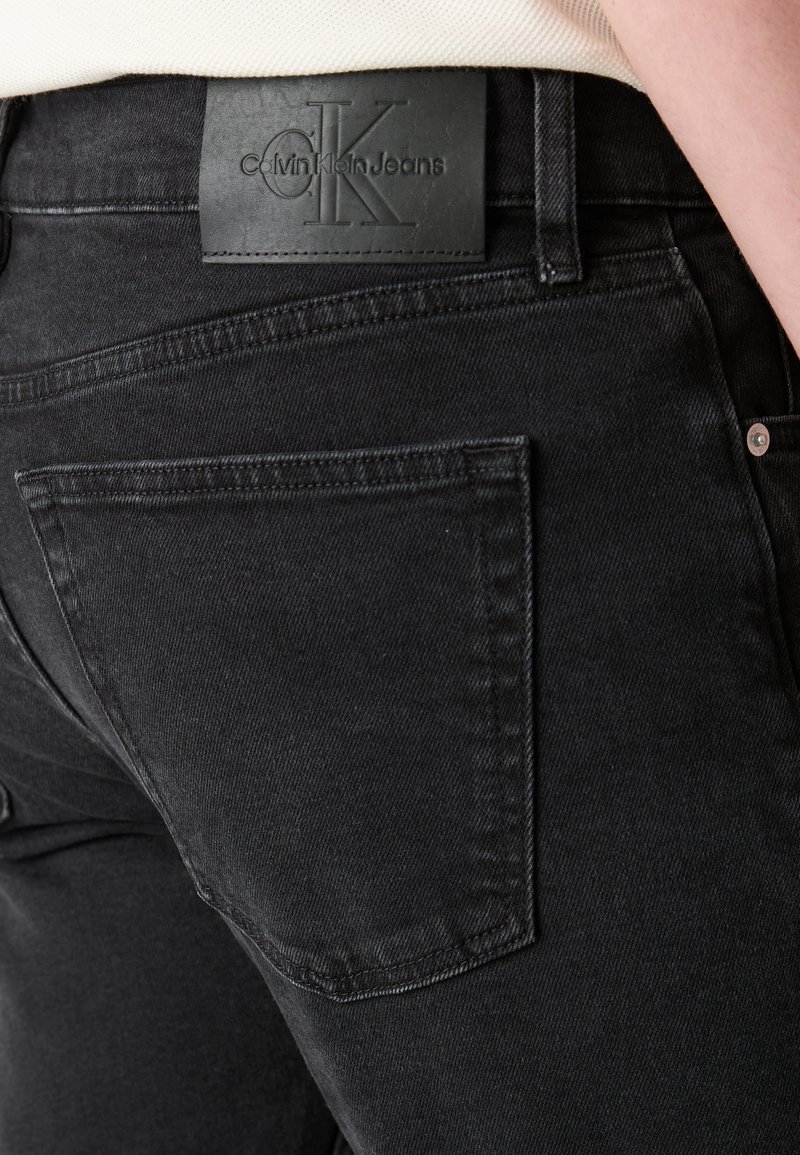 Czarne dżinsy o widocznej tylnej kieszeni, skórzana naszywka z wytłoczonym logo Calvin Klein Jeans na pasku oraz subtelne detale przeszycia.