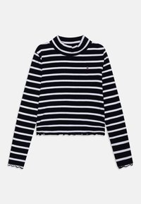 Top de cuello alto a rayas en blanco y negro con mangas largas, textura de canalé, diseño corto y dobladillo festoneado. Pequeño logo en el pecho.