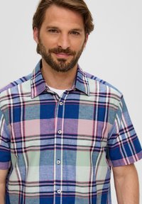 Camicia a maniche corte a quadri con motivi blu, verde, rosa e grigio, con colletto abbottonato e cinque bottoni frontali. Tessuto in cotone.