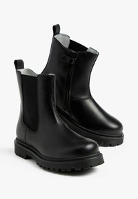 Stivali ankle in pelle nera con pannelli elastici laterali e chiusura con zip, dotati di suola in gomma testurizzata e punta rotonda.