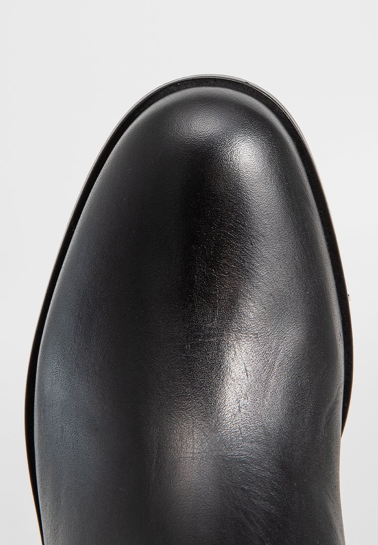 Stivale in pelle nera con punta arrotondata, texture liscia e cuciture minime. La suola è leggermente elevata e presenta un design elegante.