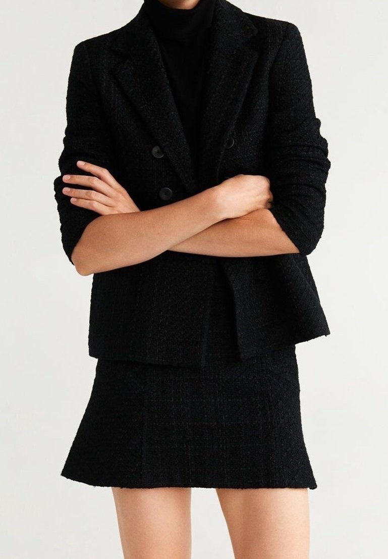 Ensemble blazer et jupe noir sur mesure, tissu texturé, design croisé à double boutonnage, boutons ronds, coupe ajustée, et jupe courte évasée.