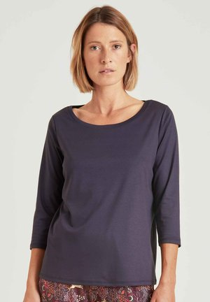 Marineblauwe lange mouwen shirt, ronde halslijn, zachte stof, fitted ontwerp, minimale naden, gecombineerd met gebloemde broek.
