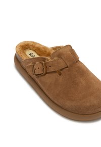 Brune ruskindssko med blødt pelsfor, en smal spænde-strop og en komfortabel sål. Har en rund tå og minimalistisk design.