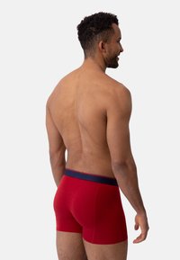 Rode stretchstof boxershorts met een marineblauwe tailleband, voorzien van een strakke pasvorm en een gladde textuur, gezien van achteren.