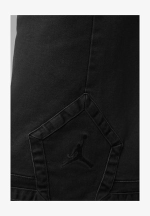 Črne kavbojke iz jeansa z teksturirano tkanino, edinstvenim žepnim dizajnom v obliki diamanta in vtisnjenim logotipom skakajoče figure.