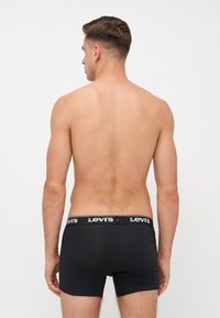 Fekete pamut alsónadrág, kontrasztos fehér Levi's logós derékpánttal. A design egyszerű, szoros illeszkedésű és sima tapintású.