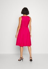 Fuchsiové bezramínkové šaty s upnutým živůtkem, rozšířenou sukňou a zavázaným pasem. Na zadní straně je jemné zapínání na knoflík. Hladká bavlněná tkanina.