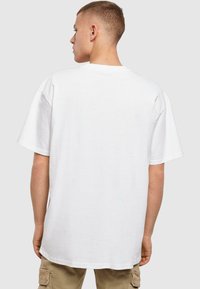 Fehér, rövid ujjú, oversize pamut póló, kerek nyakkal és laza szabással, sima textúrával, látható minták nélkül.