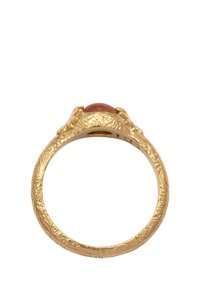 Guldtexturerad ring med en rund rödbrun ädelsten i en kloliknande design med intrikata detaljer runt ringen.