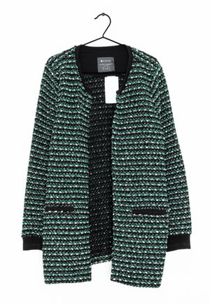 Cardigan lavorato a maglia con texture nera, verde e bianca, maniche lunghe e due tasche frontali, appeso a una gruccia nera.
