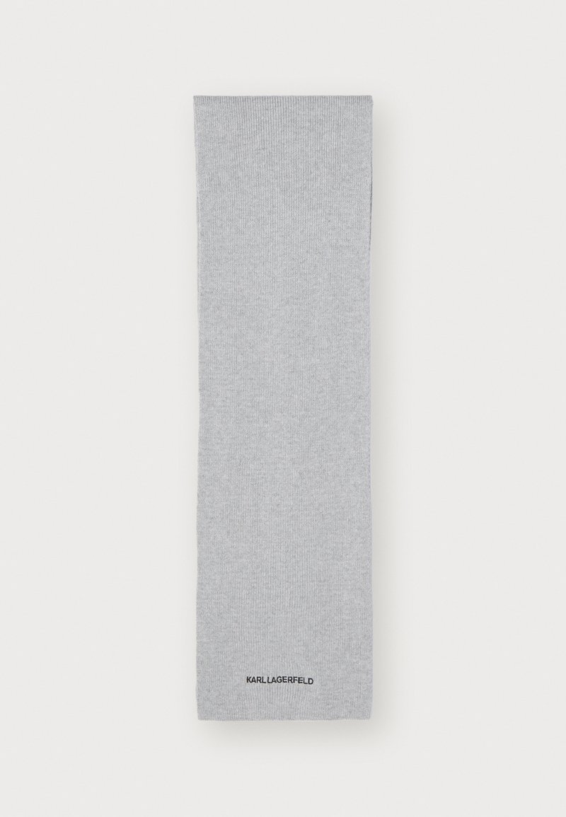 Sive rebraste nogavice iz mehke tkanine, ki imajo diskretno teksturo in črn logotip na dnu.