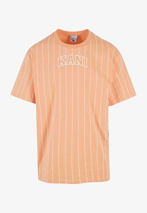 Kortermet oransje t-skjorte med hvite vertikale striper, med ordet "KANI" i fet hvit skrift på forsiden. Laget av bomull.