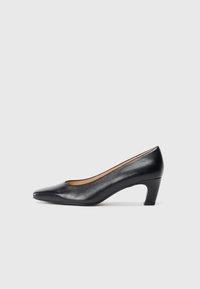 Sorte lær mid-heel pumps med spiss tå og buet blokkhæl, vist i profil på en enkel lys grå bakgrunn.
