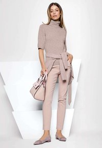 Helles rosa Rollkragensweater, tailliert; passende schmale Hose; graue Ballerinas; strukturierte Handtasche mit zweifarbigen Akzenten.