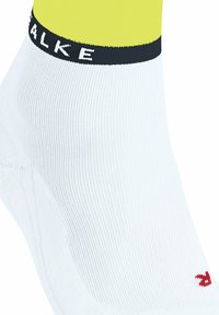 Calzino sportivo bianco con finitura testurizzata, dotato di un polsino giallo e di una fascia blu navy con testo "SFALE"; piccolo dettaglio del logo rosso visibile.